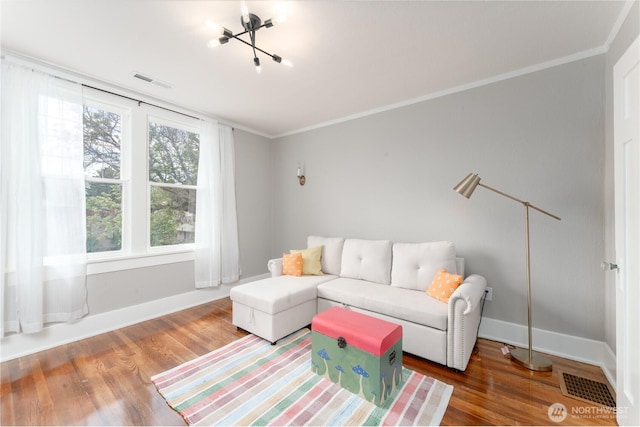 living room featuring baseboards, ornamental molding, wood finished floors, and visible vents