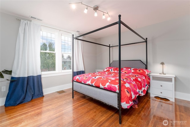 bedroom featuring baseboards, visible vents, and wood finished floors
