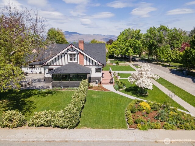 rear view of property with a lawn, a chimney, and a mountain view