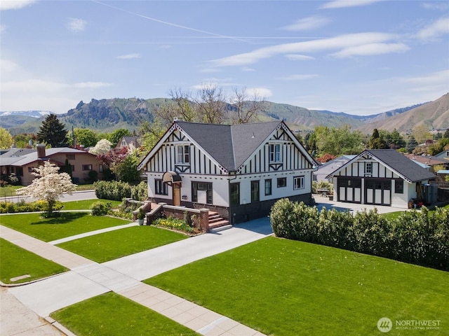 tudor home with board and batten siding, a mountain view, and a front yard