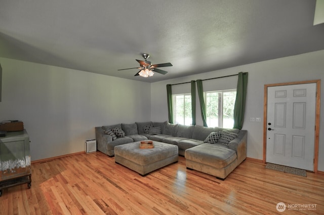 living room featuring light wood-type flooring, baseboards, and ceiling fan