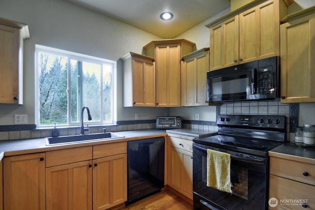 kitchen with light wood-style floors, black appliances, recessed lighting, a sink, and backsplash