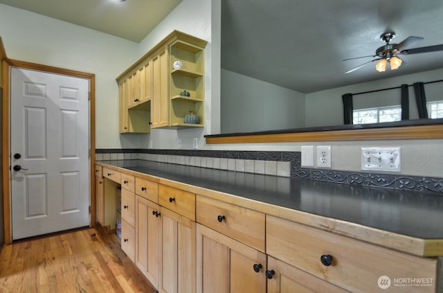 kitchen featuring light brown cabinets, open shelves, dark countertops, light wood-style floors, and ceiling fan