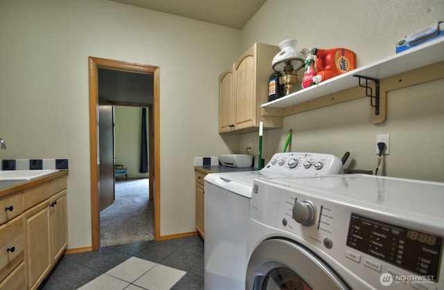 laundry area with washing machine and clothes dryer, a sink, tile patterned floors, baseboards, and cabinet space