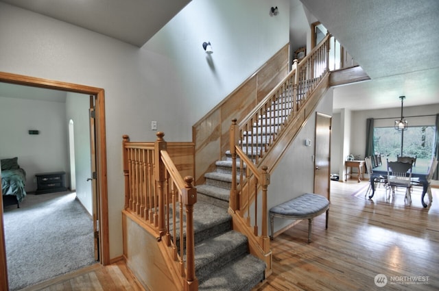 stairs featuring a towering ceiling and wood finished floors