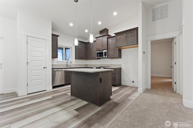 kitchen featuring a sink, a kitchen island, stainless steel appliances, visible vents, and dark brown cabinets