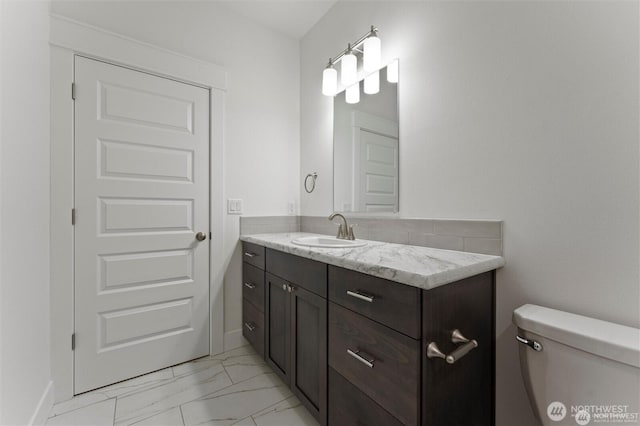 bathroom with marble finish floor, toilet, and vanity