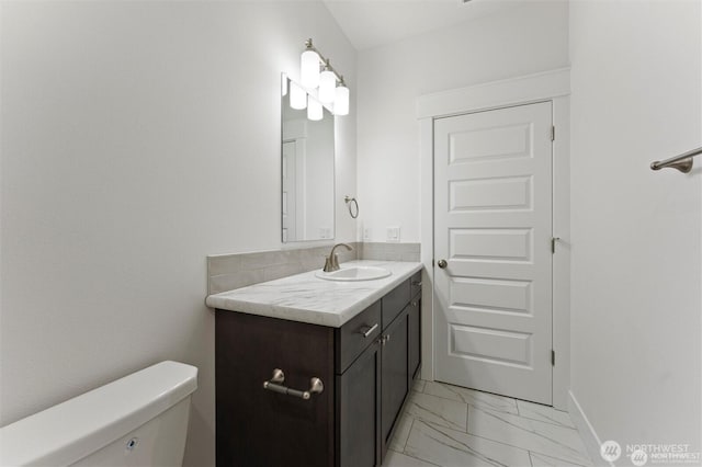 half bath with marble finish floor, vanity, toilet, and baseboards