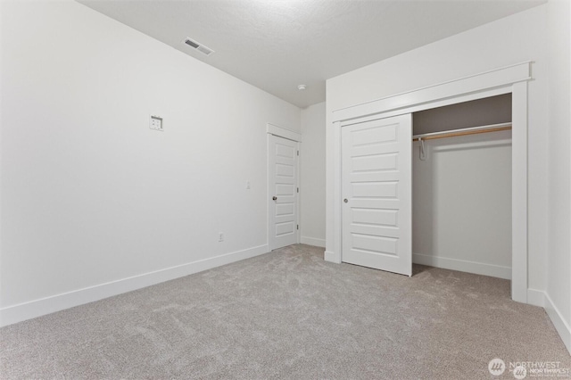 unfurnished bedroom featuring baseboards, visible vents, a closet, and carpet