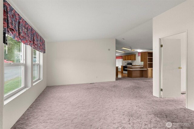 unfurnished living room featuring light carpet and vaulted ceiling