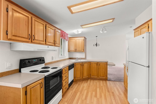 kitchen featuring white appliances, a peninsula, under cabinet range hood, a sink, and light wood finished floors