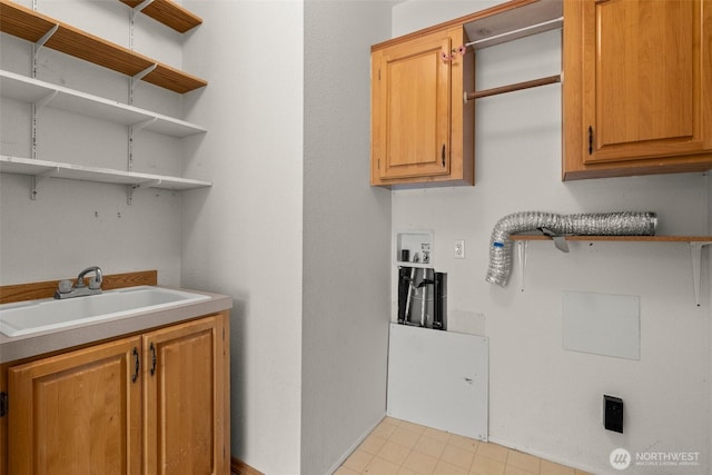 clothes washing area with cabinet space and a sink