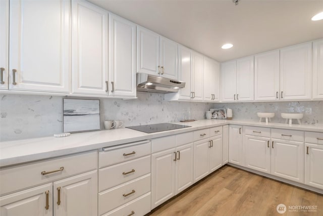 kitchen with under cabinet range hood, light wood-type flooring, light countertops, and black electric cooktop