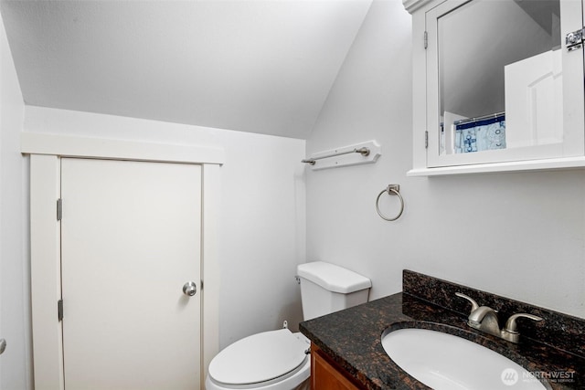 bathroom with lofted ceiling, toilet, and vanity