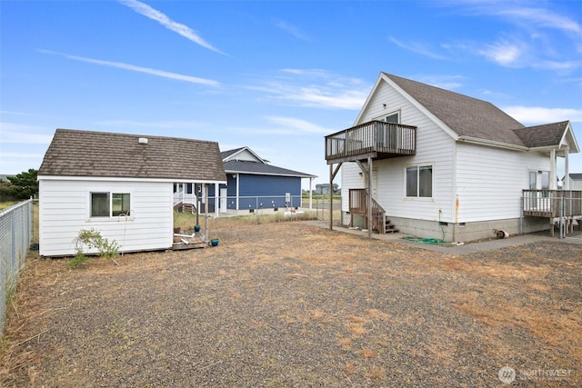 back of house with a shingled roof, an outbuilding, fence, and a storage shed