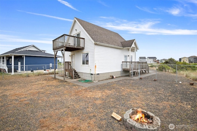 back of house with a shingled roof, a fire pit, fence, and crawl space