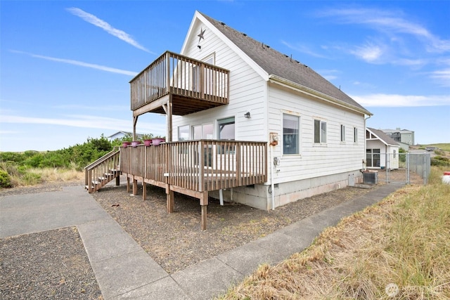 rear view of property with a shingled roof, central AC, and a wooden deck