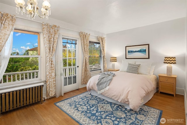 4201 N Mason St, Tacoma, WA 98407 - bedroom featuring radiator heating unit, access to exterior, a chandelier, and wood-type flooring