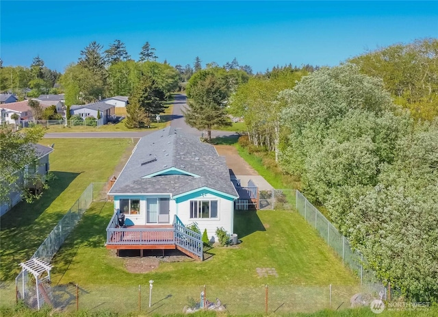 rear view of property with a fenced backyard, roof with shingles, a lawn, and a deck