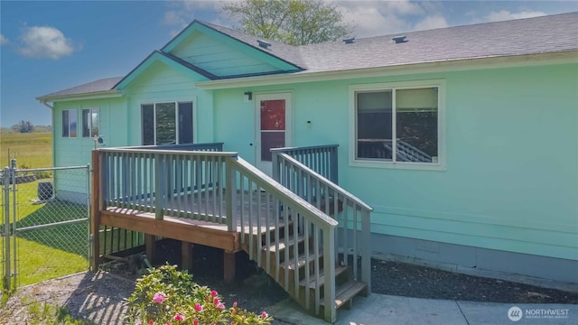 exterior space with fence, a gate, a wooden deck, and roof with shingles