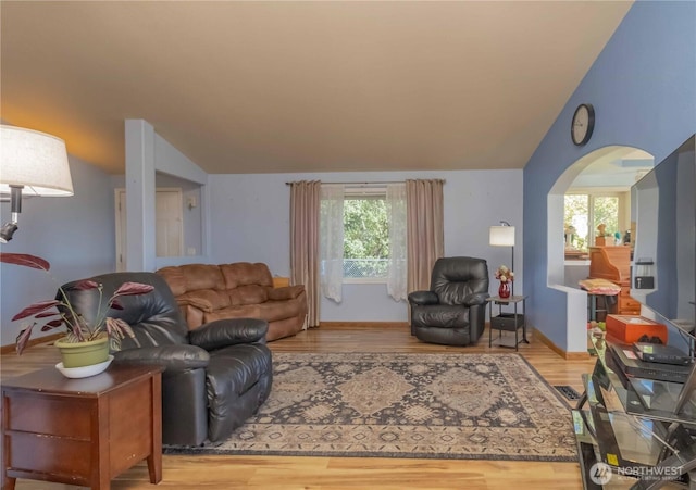 living room featuring baseboards, arched walkways, wood finished floors, and vaulted ceiling