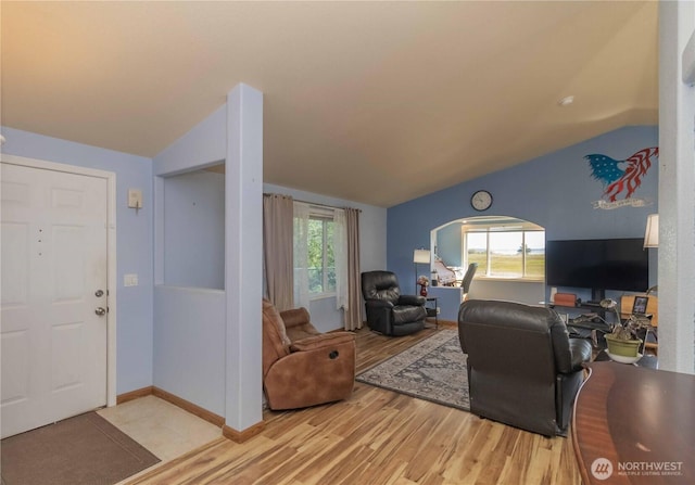 living area featuring arched walkways, vaulted ceiling, and light wood-style flooring