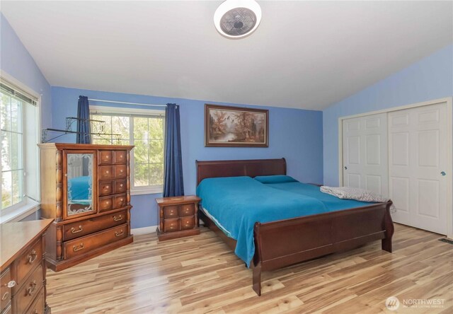 bedroom with a closet, light wood-type flooring, and lofted ceiling