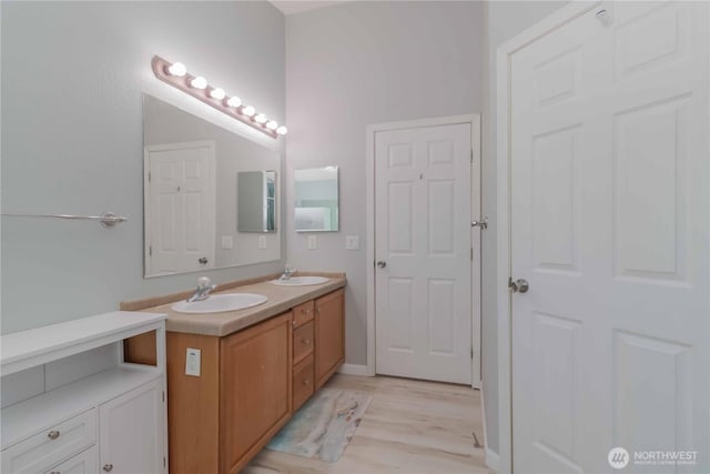 full bath with double vanity, a sink, and wood finished floors