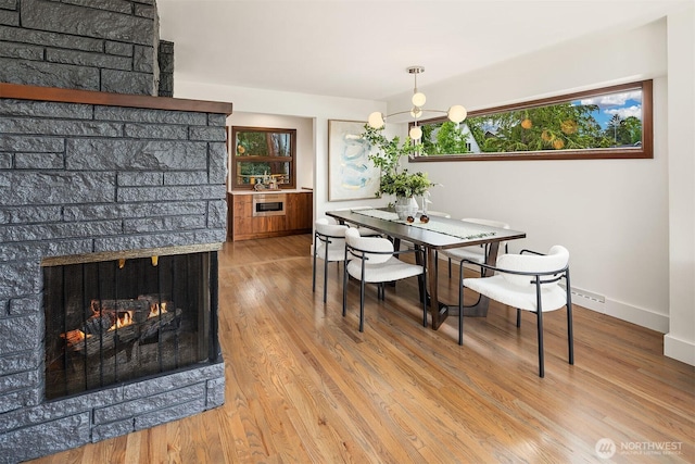 dining room featuring baseboards, wood finished floors, and a lit fireplace