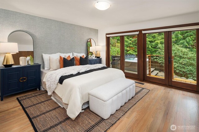 bedroom featuring wallpapered walls, access to exterior, an accent wall, light wood-type flooring, and french doors