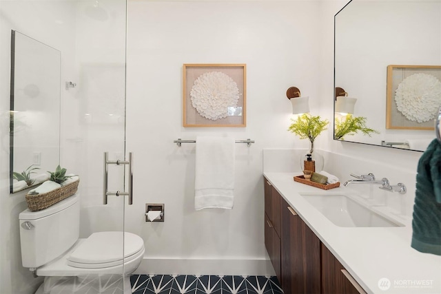 bathroom featuring toilet, vanity, an enclosed shower, and baseboards