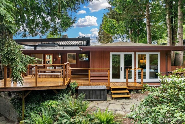 rear view of house with french doors, a wooden deck, and a chimney