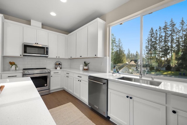 kitchen featuring recessed lighting, white cabinets, a sink, appliances with stainless steel finishes, and backsplash
