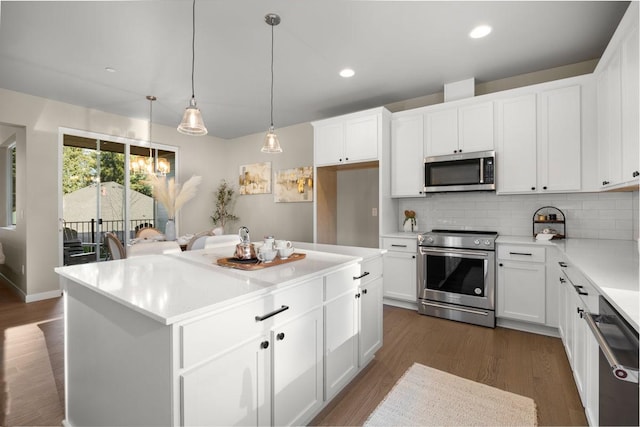 kitchen with a kitchen island, dark wood-type flooring, white cabinetry, appliances with stainless steel finishes, and backsplash