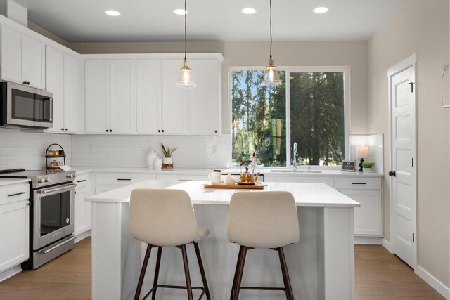kitchen with a sink, appliances with stainless steel finishes, backsplash, and a kitchen bar