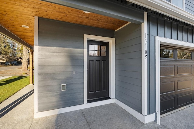 doorway to property featuring board and batten siding, a porch, and a garage