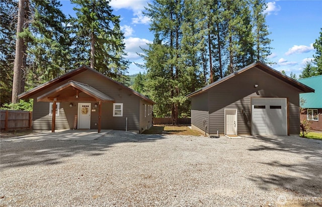 view of front of house featuring gravel driveway, an outbuilding, fence, and a detached garage