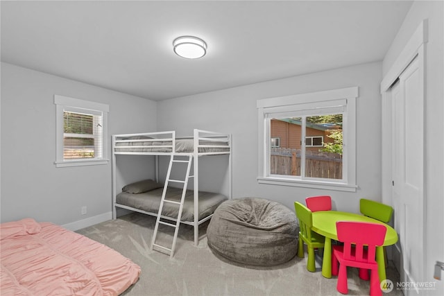 carpeted bedroom with a closet and baseboards