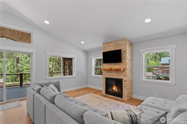 living area with vaulted ceiling, a fireplace, light wood-type flooring, baseboards, and recessed lighting