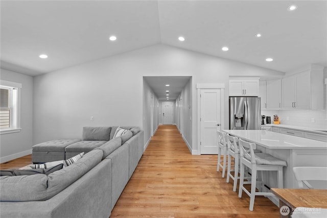 living area featuring light wood-style floors, vaulted ceiling, and recessed lighting