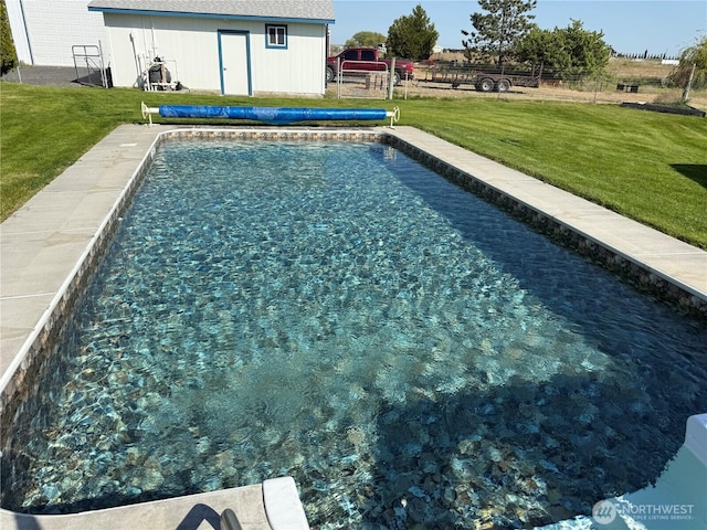 view of swimming pool featuring a yard, an outdoor structure, and a covered pool