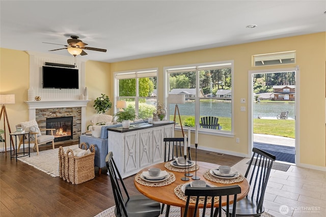 1140 Twin Lakes Rd, Cle Elum, WA 98922 - dining space with ceiling fan, a stone fireplace, baseboards, dark wood finished floors, and a water view