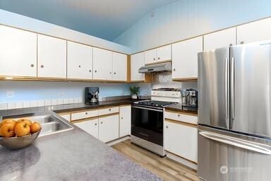 36850 12th Ave S, Federal Way, WA 98003 - kitchen featuring freestanding refrigerator, stove, lofted ceiling, under cabinet range hood, and white cabinetry