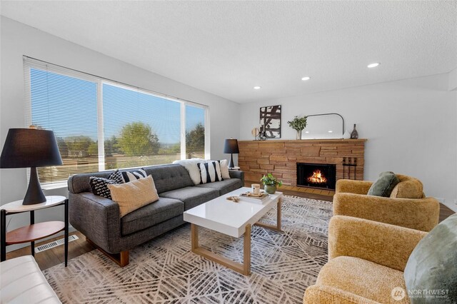 living room featuring a stone fireplace, recessed lighting, light wood-style flooring, and visible vents
