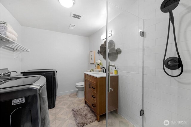 full bath featuring visible vents, vanity, washing machine and dryer, toilet, and a shower stall