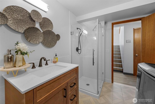 full bath with vanity, washer / dryer, and a shower stall