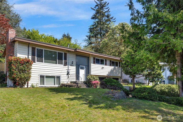 bi-level home featuring entry steps, a chimney, and a front yard