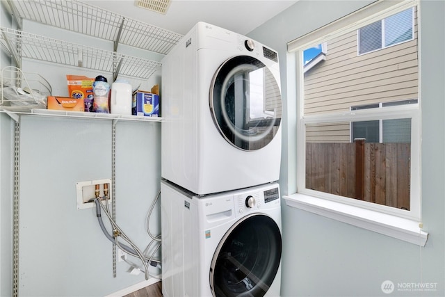 washroom with visible vents, stacked washer / drying machine, and laundry area