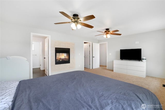 unfurnished bedroom featuring ceiling fan, a tile fireplace, and carpet