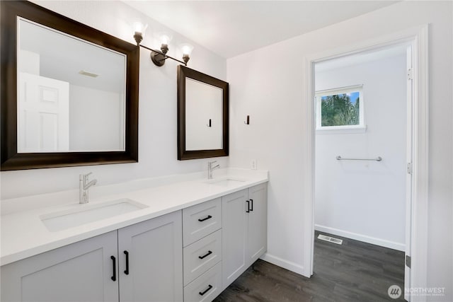 full bath with double vanity, a sink, wood finished floors, and visible vents